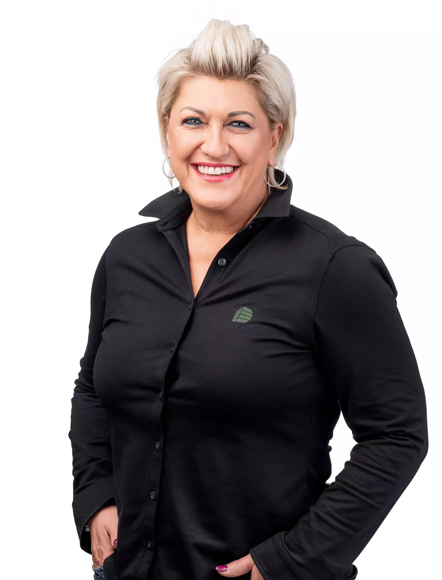 Porträt einer lächelnden Frau mit kurzen blonden Haaren in schwarzem Hemd vor weißem Hintergrund, Deutinger Teammitglied