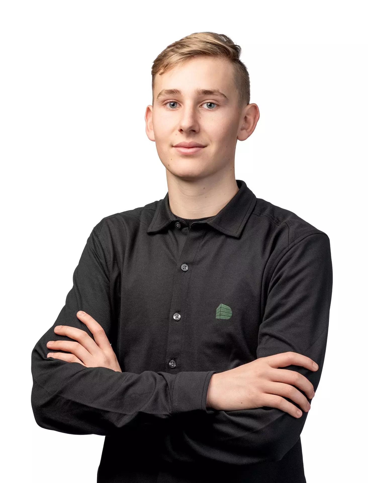 Junger Mann mit verschränkten Armen trägt schwarzes Hemd mit grünem Logo vor weißem Hintergrund für Baumanagement-Teamseite