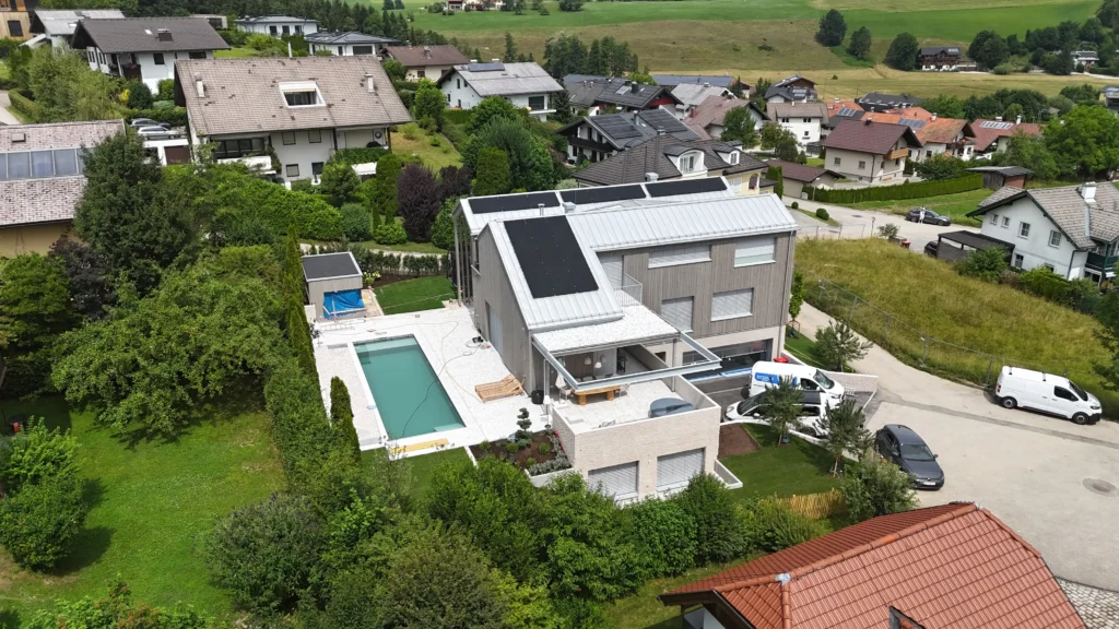 02_EFH Salzkammergut Modernes Einfamilienhaus mit Pool und Solaranlagen im Salzkammergut, umgeben von grüner Landschaft und Nachbarhäusern
