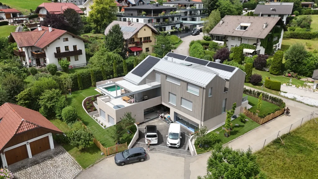 03_EFH Salzkammergut Modernes Einfamilienhaus mit Solarpaneelen im Salzkammergut umgeben von grünen Gärten und Nachbarhäusern im